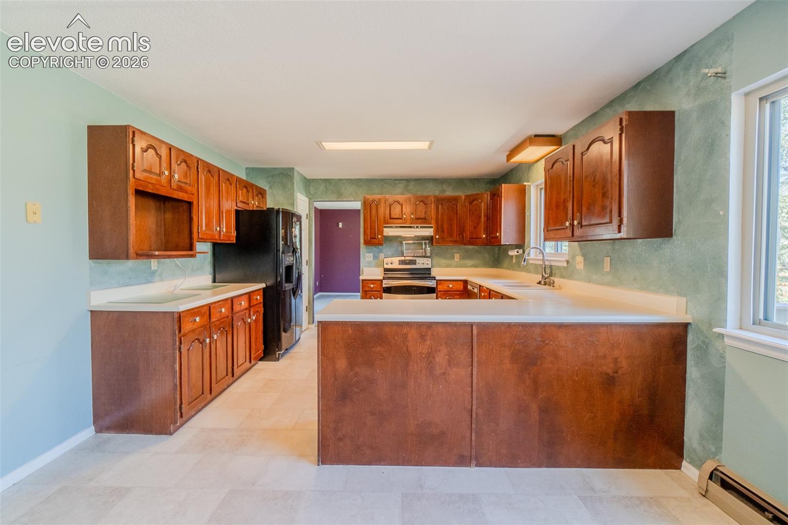 Kitchen featuring wood cabinetry, light-toned countertops, tile flooring, and integrated appliances