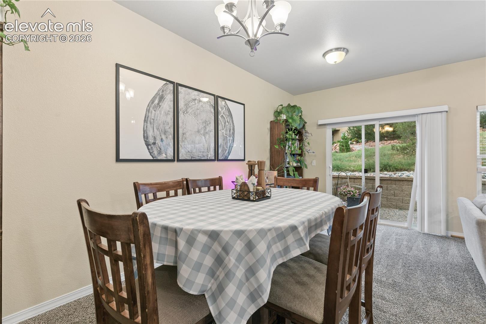 Dining area featuring neutral wall tones, carpet flooring, a sliding glass door providing exterior access, and a ceiling-mounted light fixture