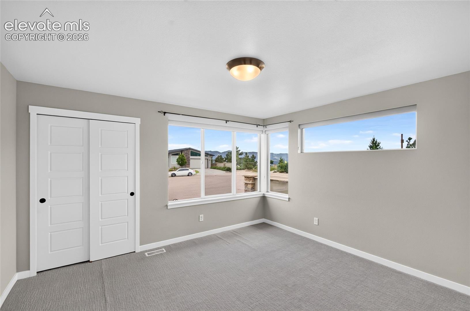 Bright room featuring light grey walls, white trim, and grey carpet flooring