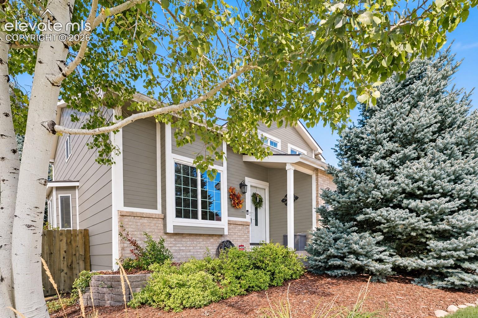 Mature landscaping, beautiful trees, and a welcoming covered entry set the stage for impressive curb appeal.