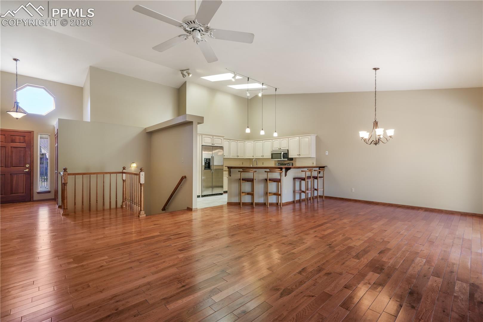 Overview of living room, dining area and kitchen with views of entry and stairs to downstairs