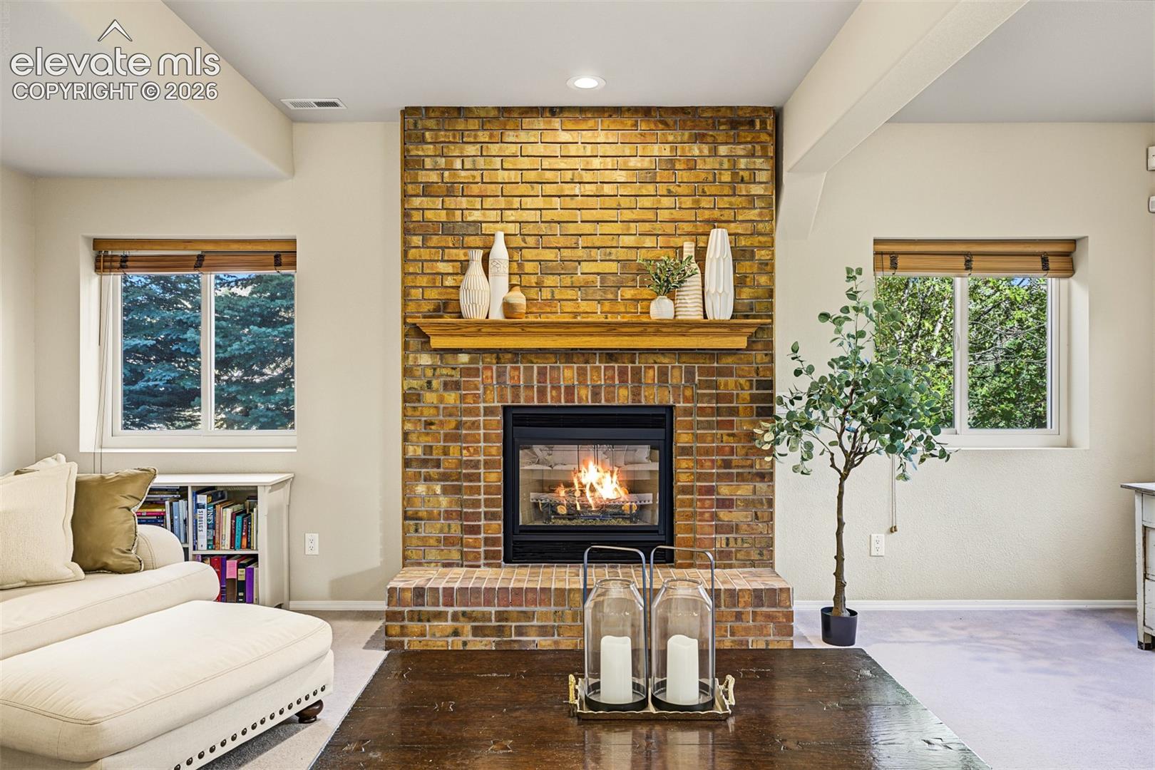 Gas-log fireplace with floor-to-ceiling brick surround, raised hearth, and mantel, creating an inviting focal point in the full walkout basement.
