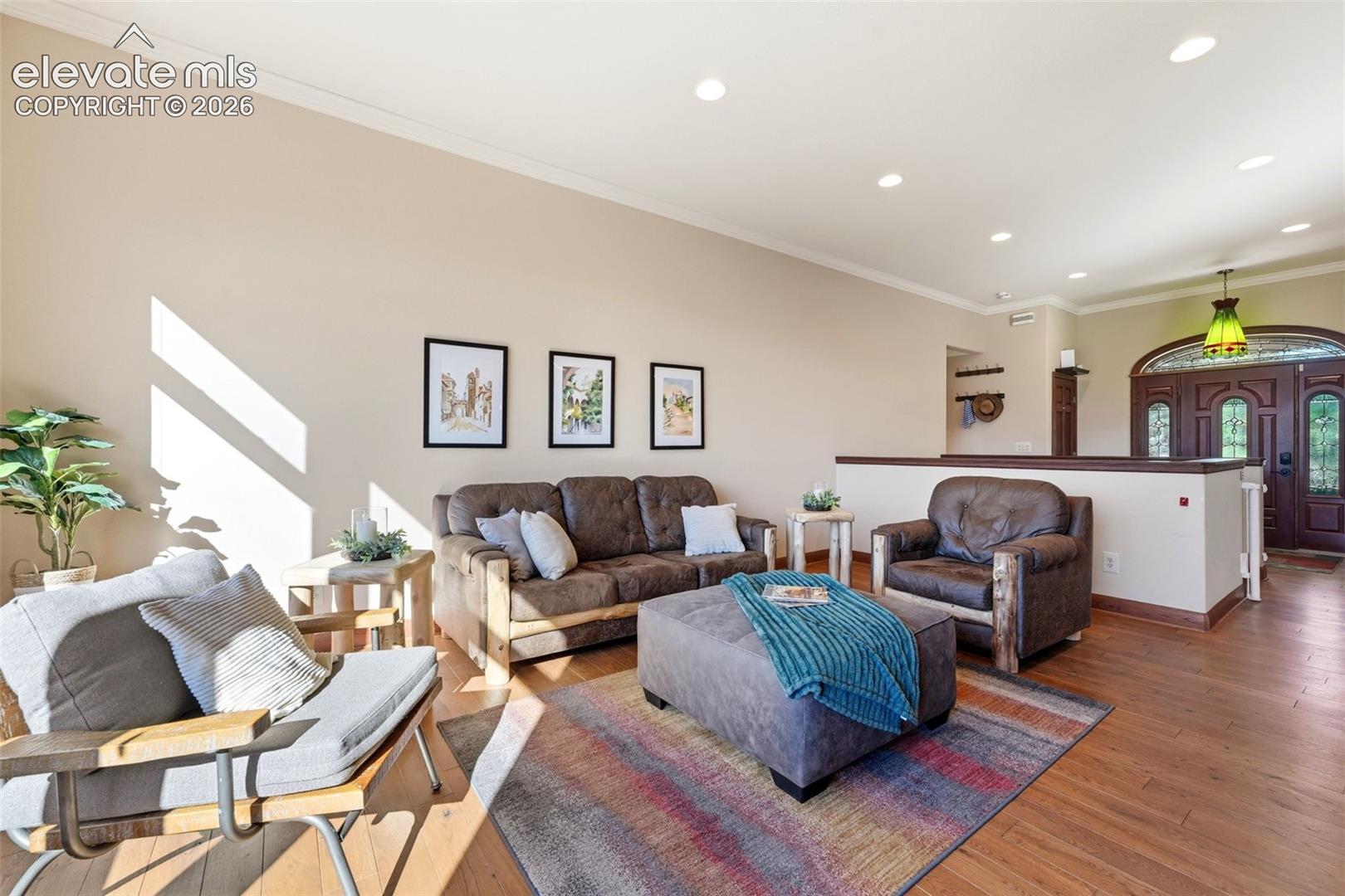 Wood-finish flooring, recessed ceiling lighting, crown molding, and an arched double-door entry