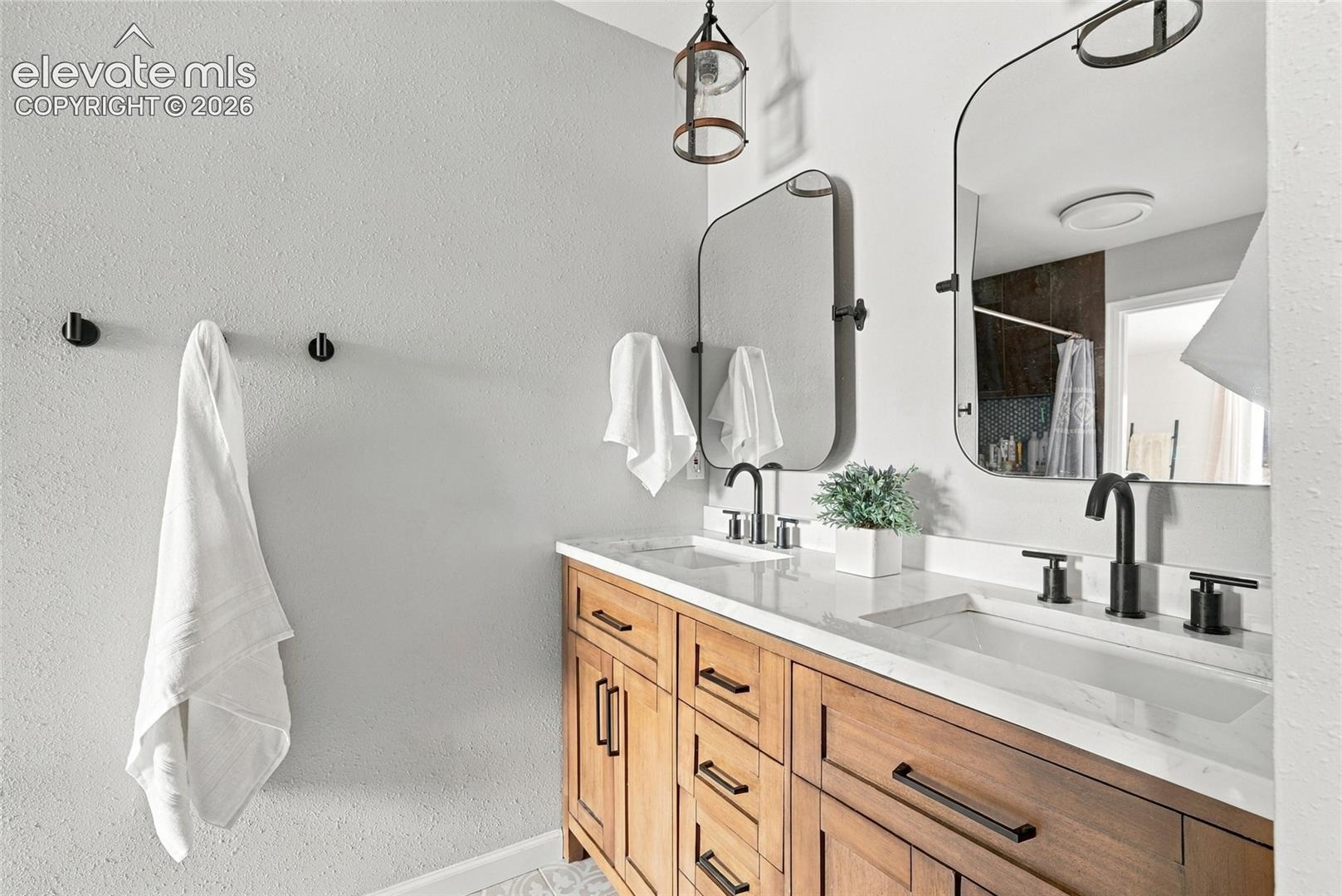 Dual vanity with wood-finish cabinetry, integrated rectangular sinks, and matte black hardware