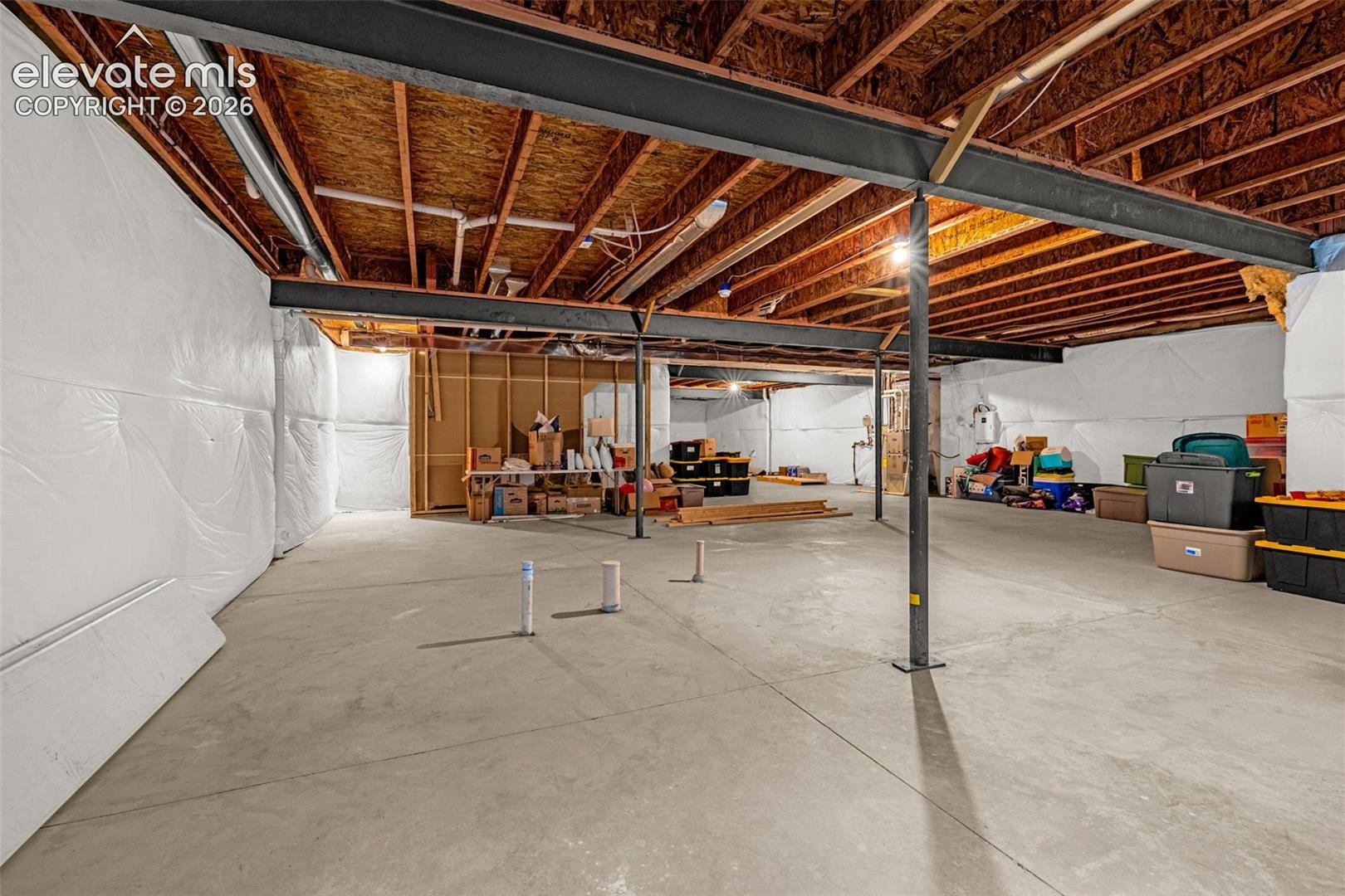 Unfinished basement with concrete flooring and exposed ceiling joists