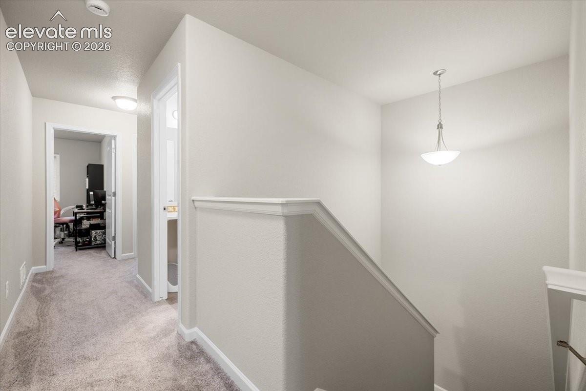 Carpeted hallway with flush-mount lighting, leading to an interior room with a desk