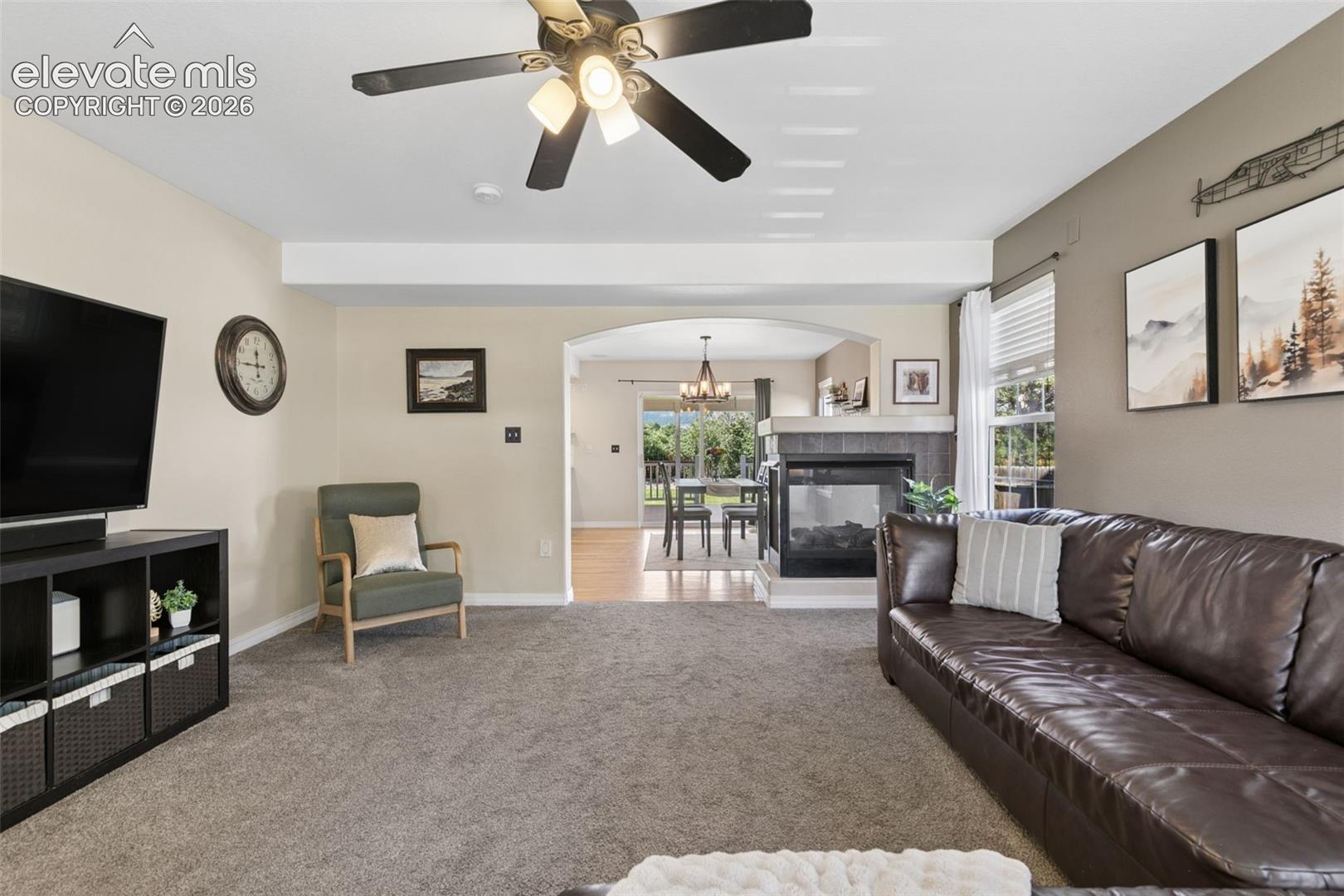 Carpeted living area with a ceiling fan light fixture