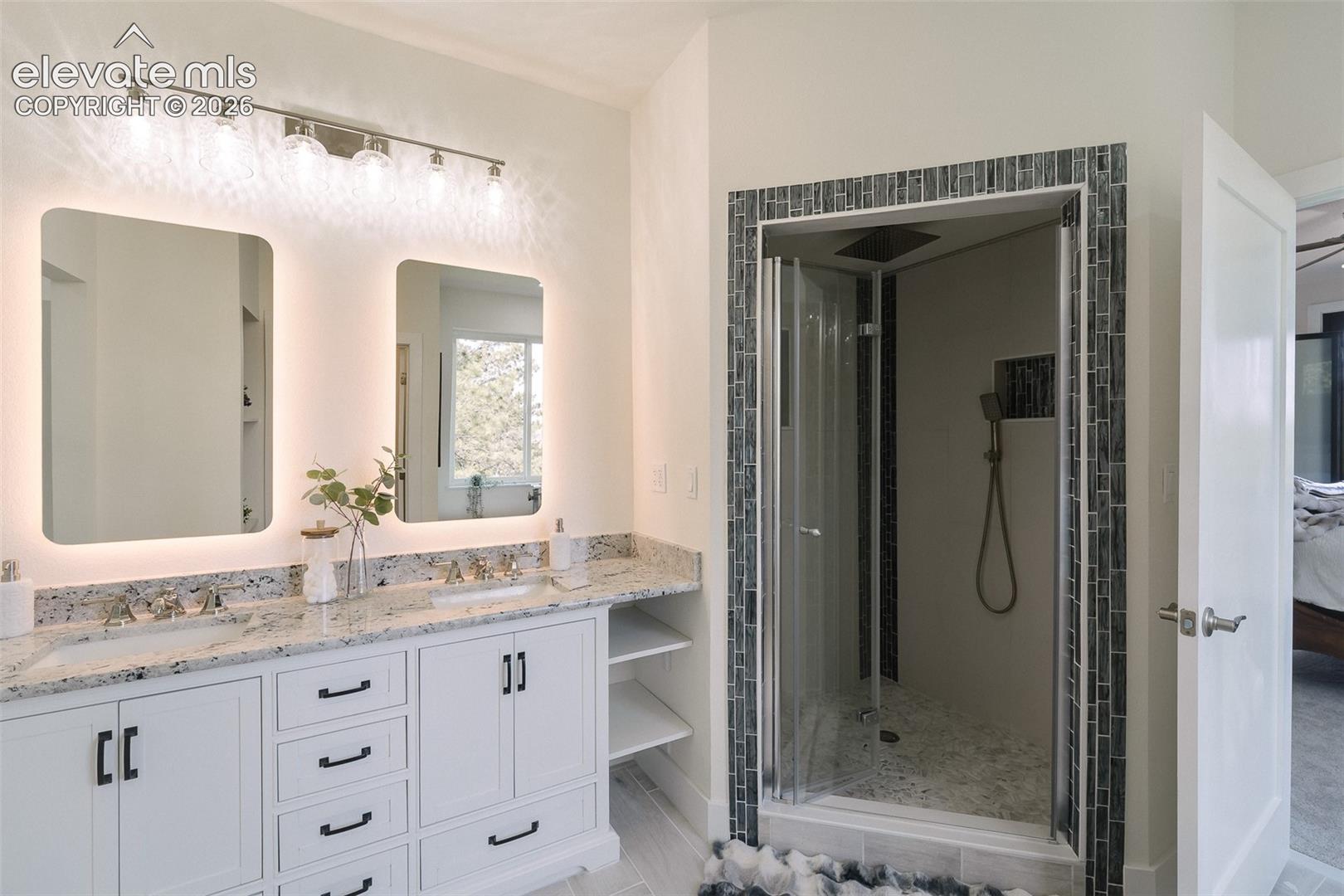 Vanity and tiled walk in shower with rain shower head and interior light in the Primary Bathroom.
