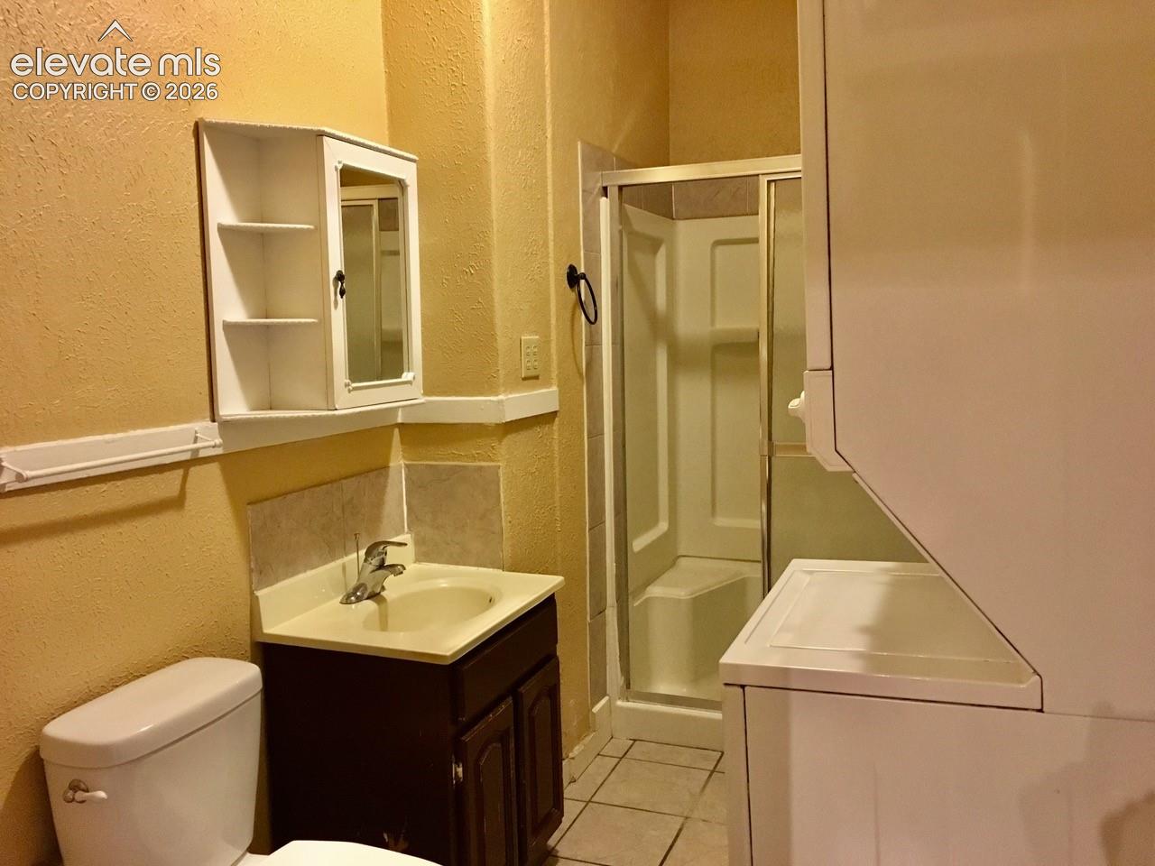 Bathroom featuring a vanity with a base cabinet, a built-in shower stall with a glass enclosure, and a wall-mounted medicine cabinet with shelving