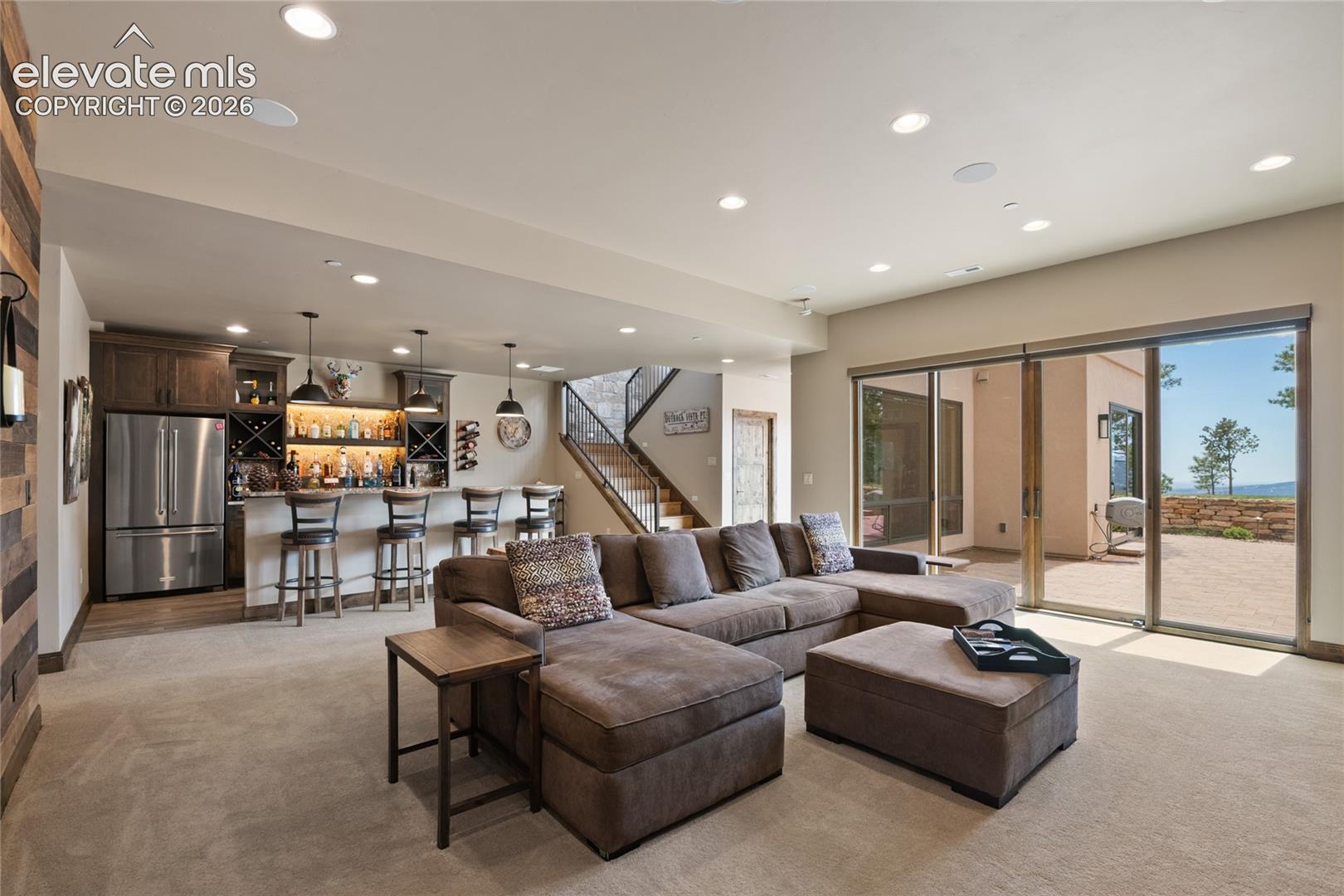 Sink in and stay awhile. Cozy lounge featuring a see-through linear fireplace, mounted TV, surround sound, and sliding glass doors to the lower patio.
