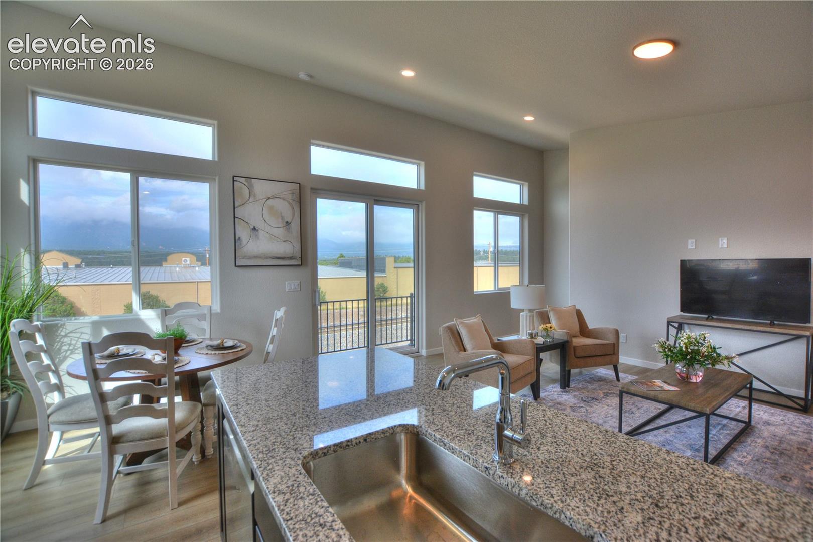 Open-concept living area with vaulted ceilings, recessed lighting, and large windows