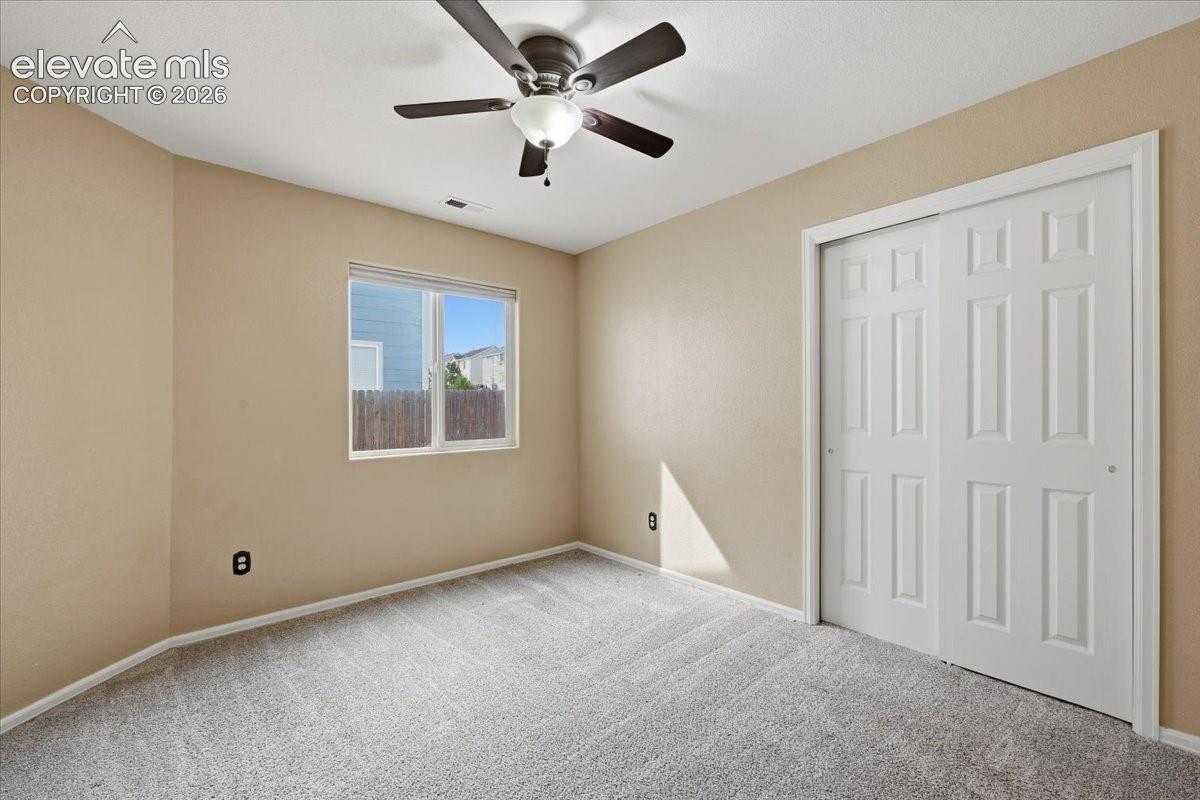 Recessed window, paneled bi-fold closet doors, ceiling fan with integrated lighting, and carpeted flooring
