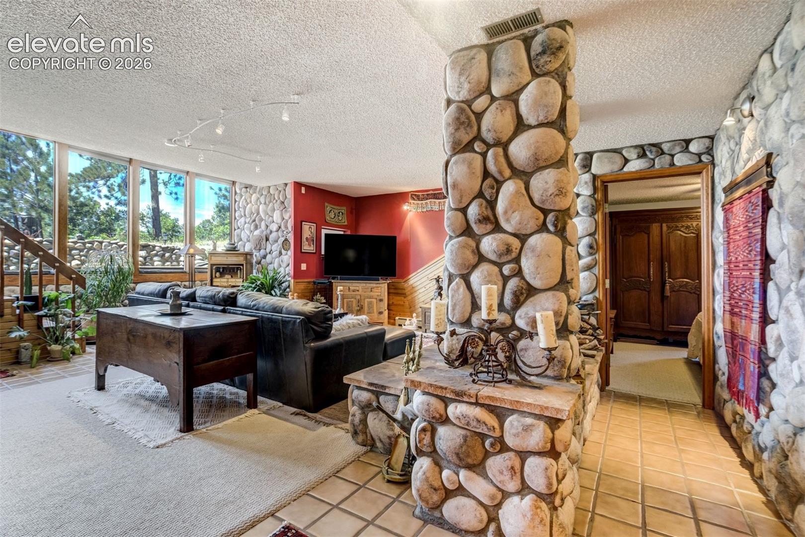 Awesome rock accents frame in the wood burning fireplace and wall of windows for the views