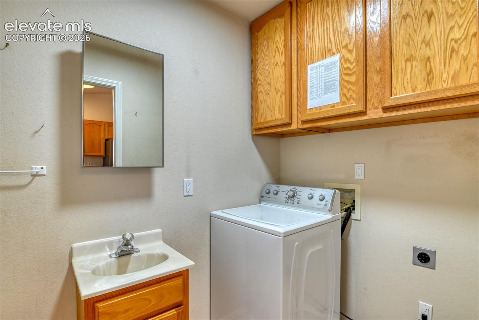 Laundry area featuring wood-finish upper cabinetry, a pedestal sink with a chrome faucet, and a wall-mounted medicine cabinet