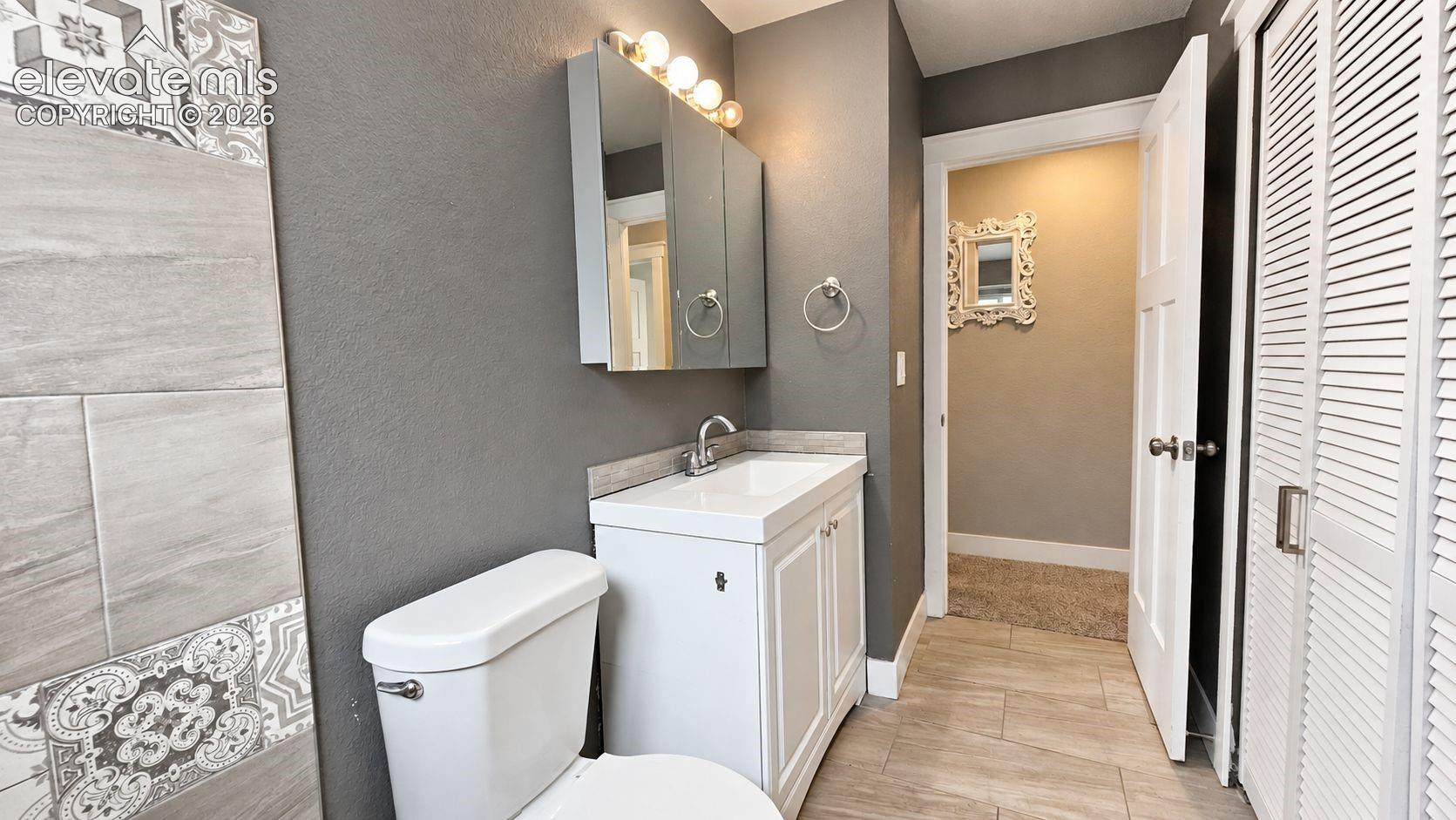 Bathtub with surrounding tile, single window, upgraded sink, chrome-finish faucet, and mirrored medicine cabinet