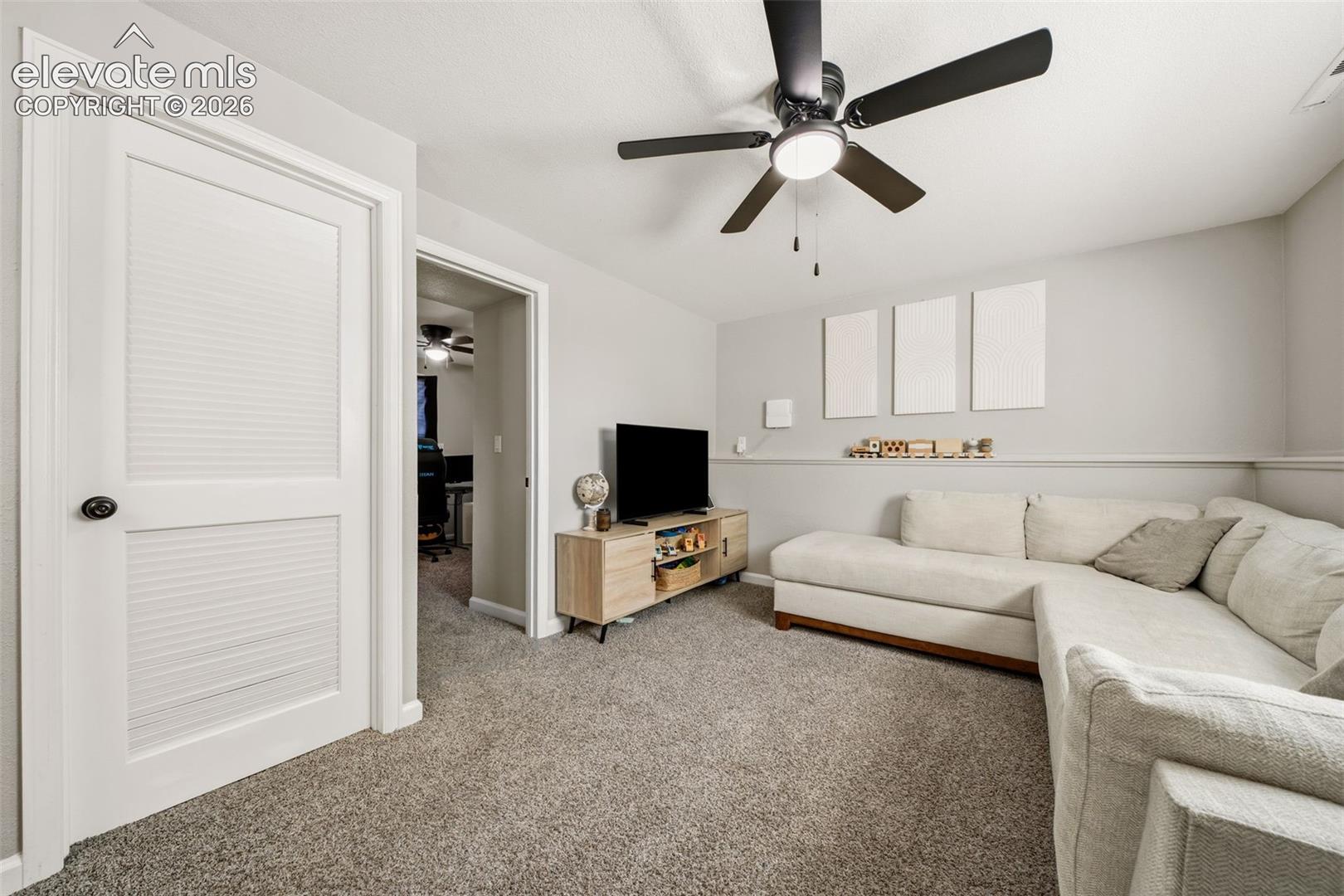 Ceiling fan with light fixture, carpet flooring, chair rail molding, and white interior doors