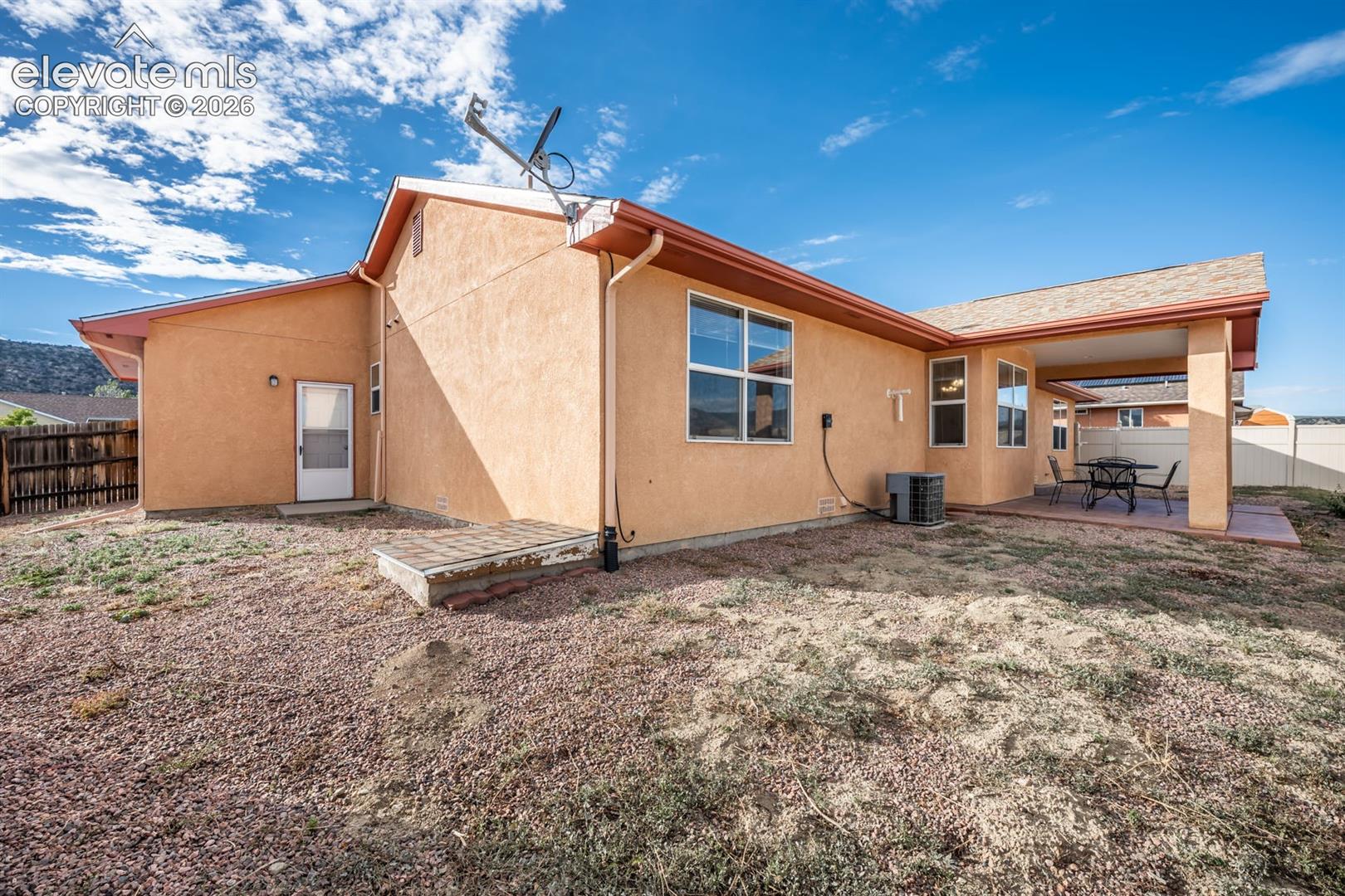 Stucco exterior featuring a covered patio, shingle roof, dual-pane windows, and fenced perimeter