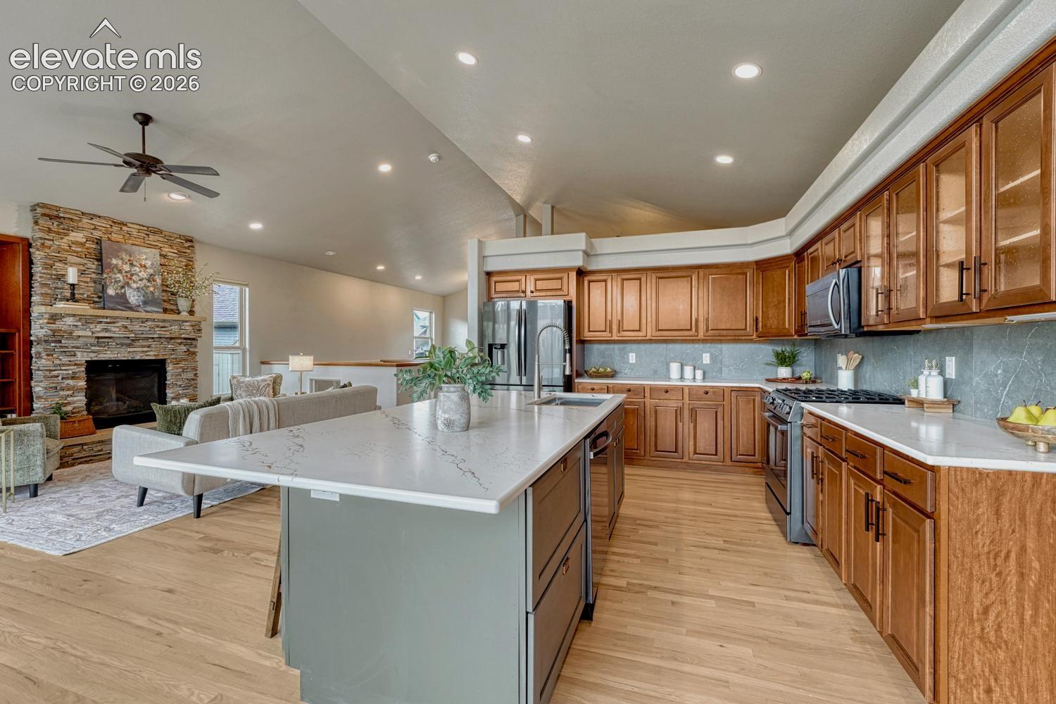 The gourmet kitchen showcases quartz countertops, a large island, abundant cabinetry, black stainless steel appliances, & New Gen lighting.