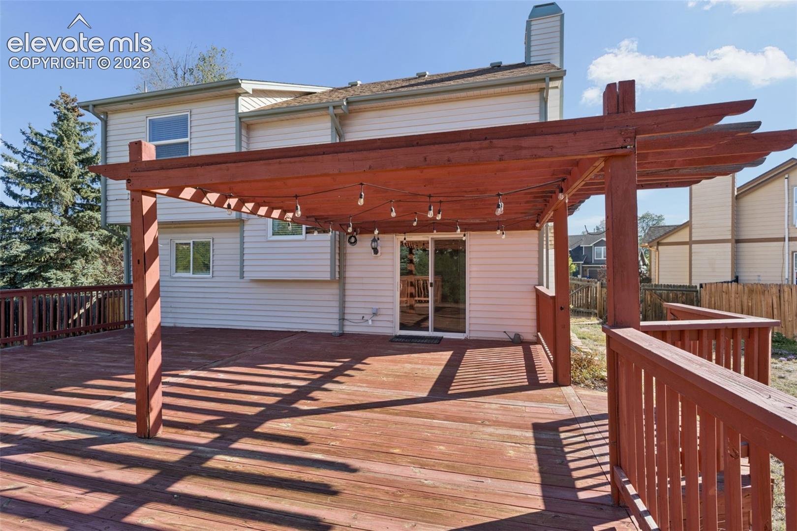 Expansive wood deck with a built-in pergola, offering direct access to the interior via sliding glass doors