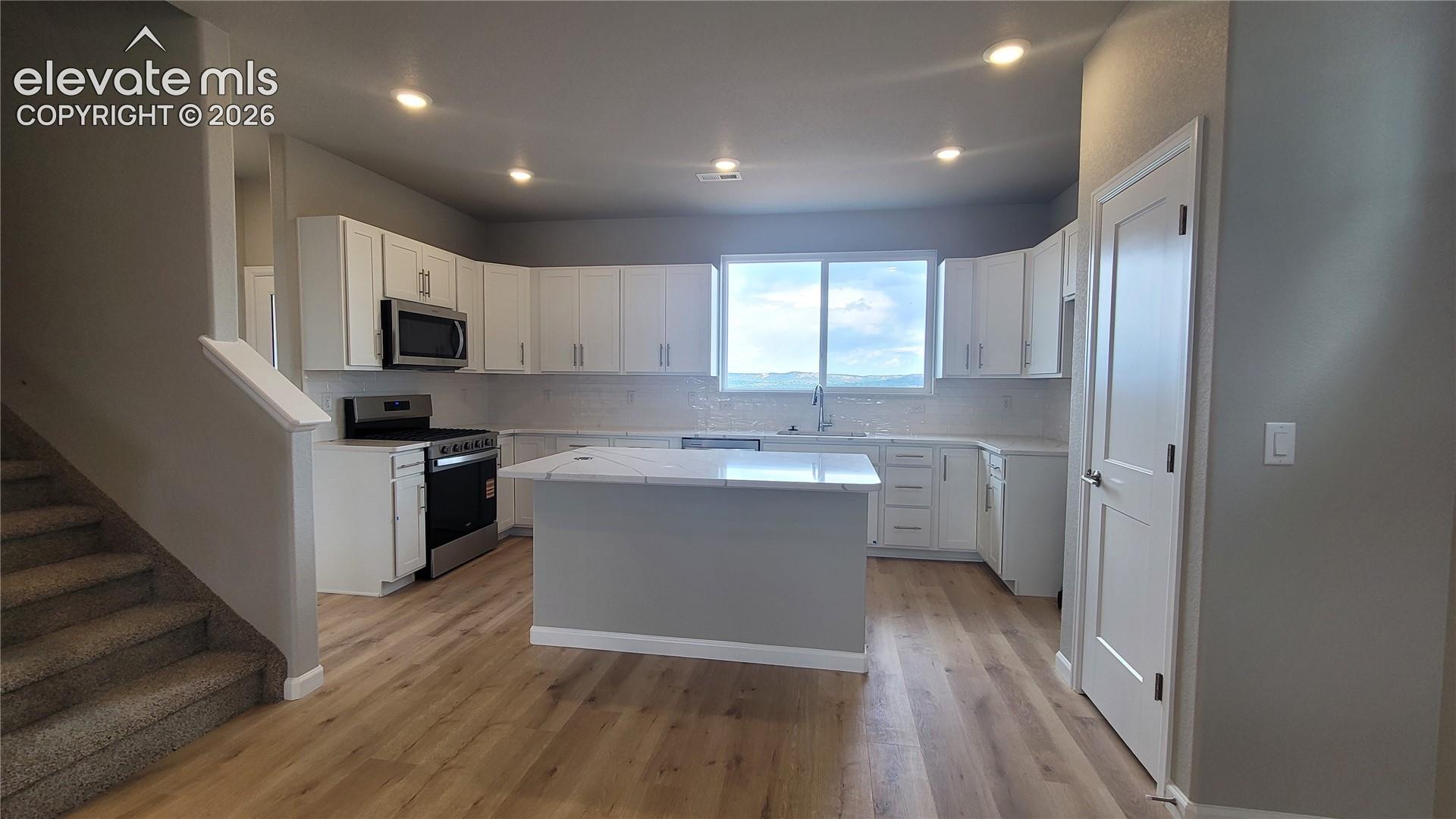 Grand Kitchen with quartz countertops, plenty of cabinets, pantry, island providing additional seating, and stainless steel gas range, microwave, and dishwasher! 