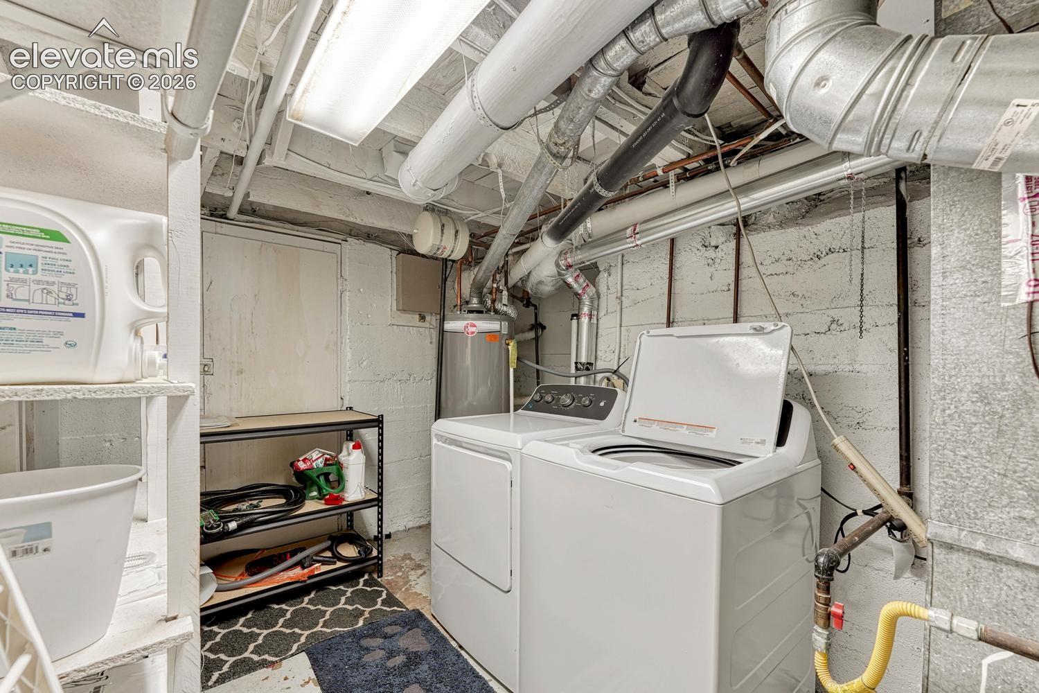 Utility area featuring laundry appliances, exposed plumbing, and overhead fluorescent lighting