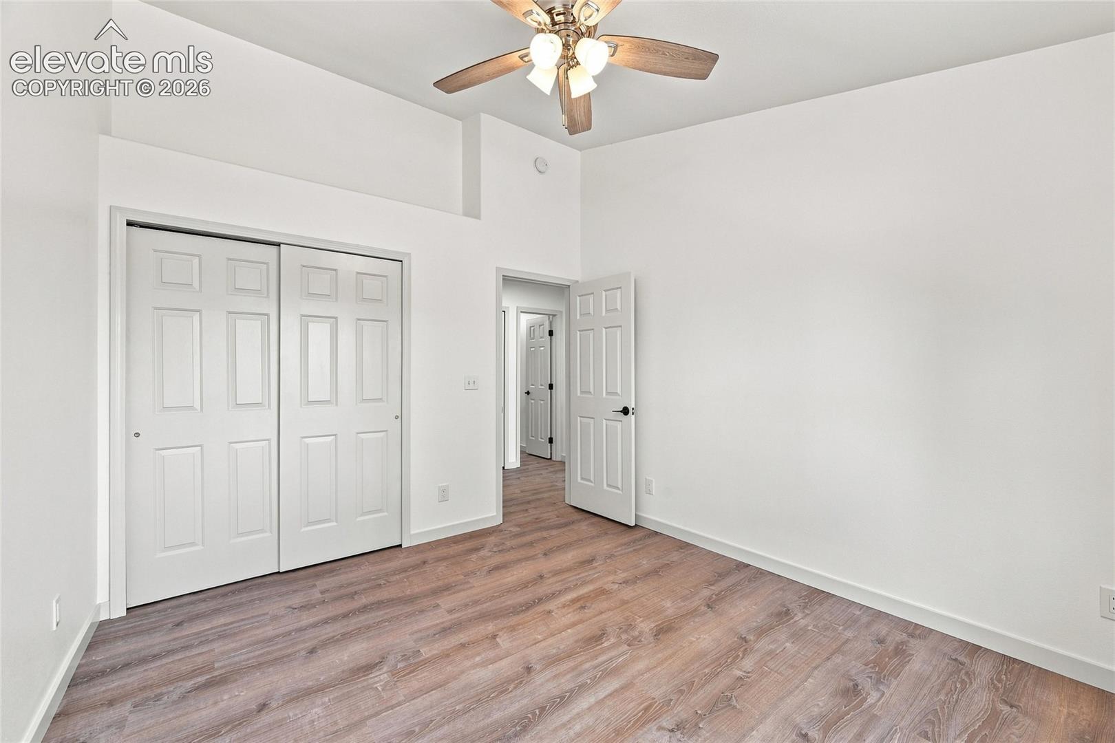 Wood-finish flooring, white walls, and a ceiling fan with integrated lighting
