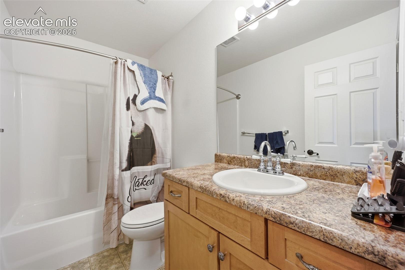 Bathroom featuring a full vanity with an integrated sink, a large mirror, and a full bathtub with an overhead shower