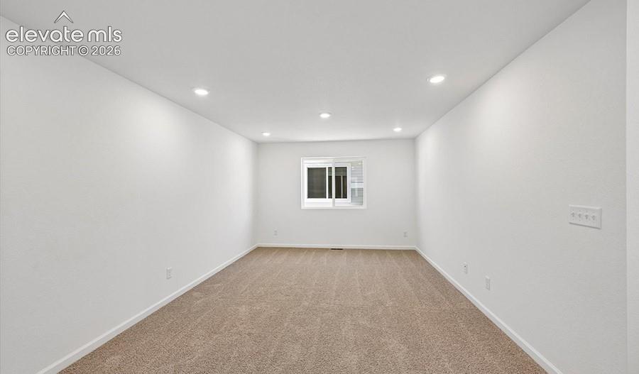 Neutral-toned interior space featuring wall-to-wall carpeting, recessed ceiling lighting, and a horizontal sliding window