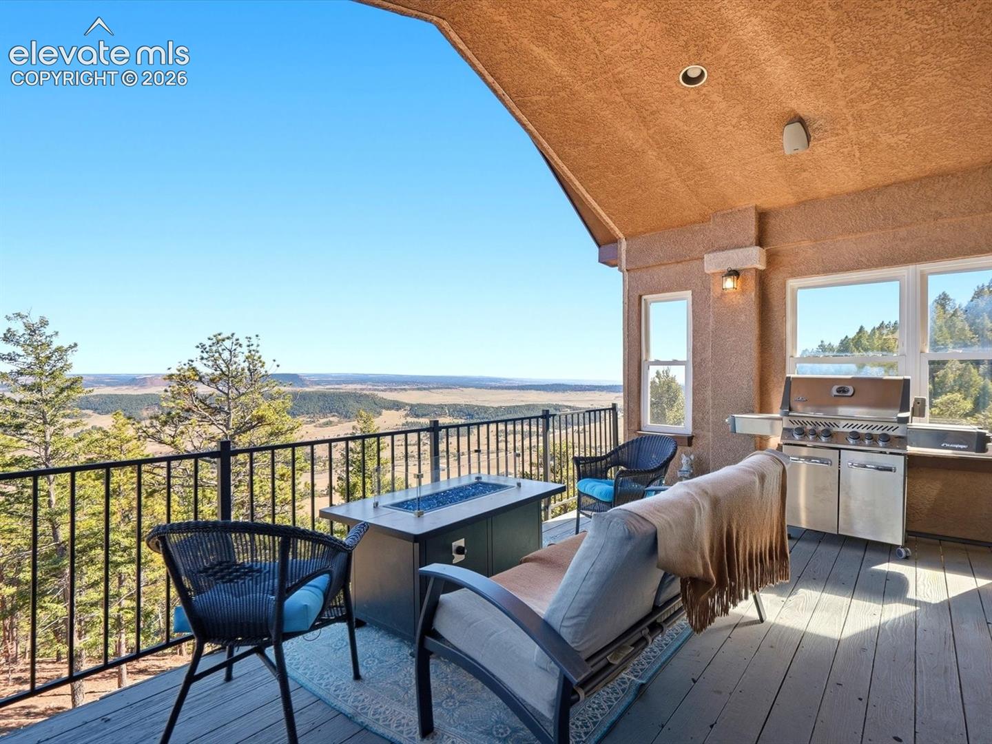 Covered deck featuring a textured stucco ceiling, built-in stainless steel grill, metal railing, and expansive mountain and valley scenery