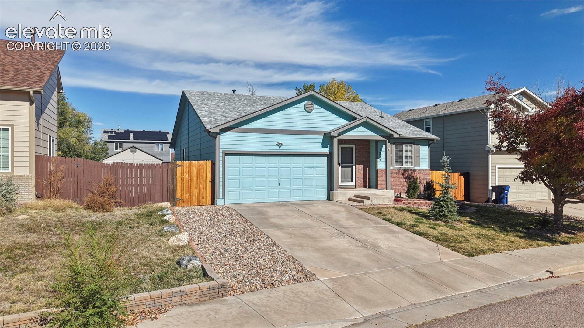 Single-story exterior featuring light blue horizontal siding, a brick accent facade, an attached two-car garage, and a concrete driveway