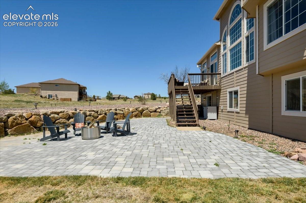 Expansive paver patio featuring a stacked stone retaining wall