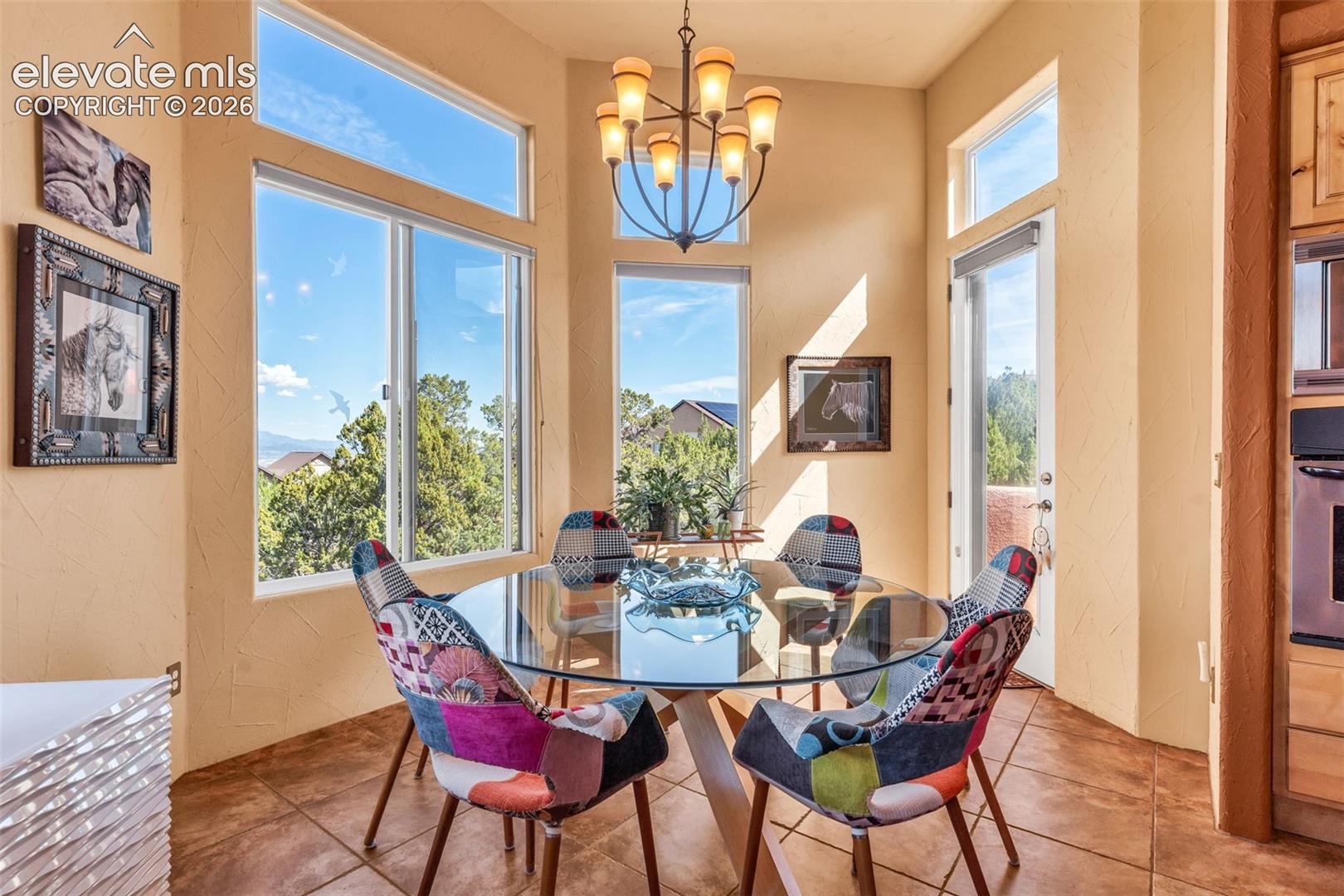 Breakfast nook featuring a multi-paneled bay window, high ceilings, tile flooring, an ornate multi-arm chandelier, and an exterior access door