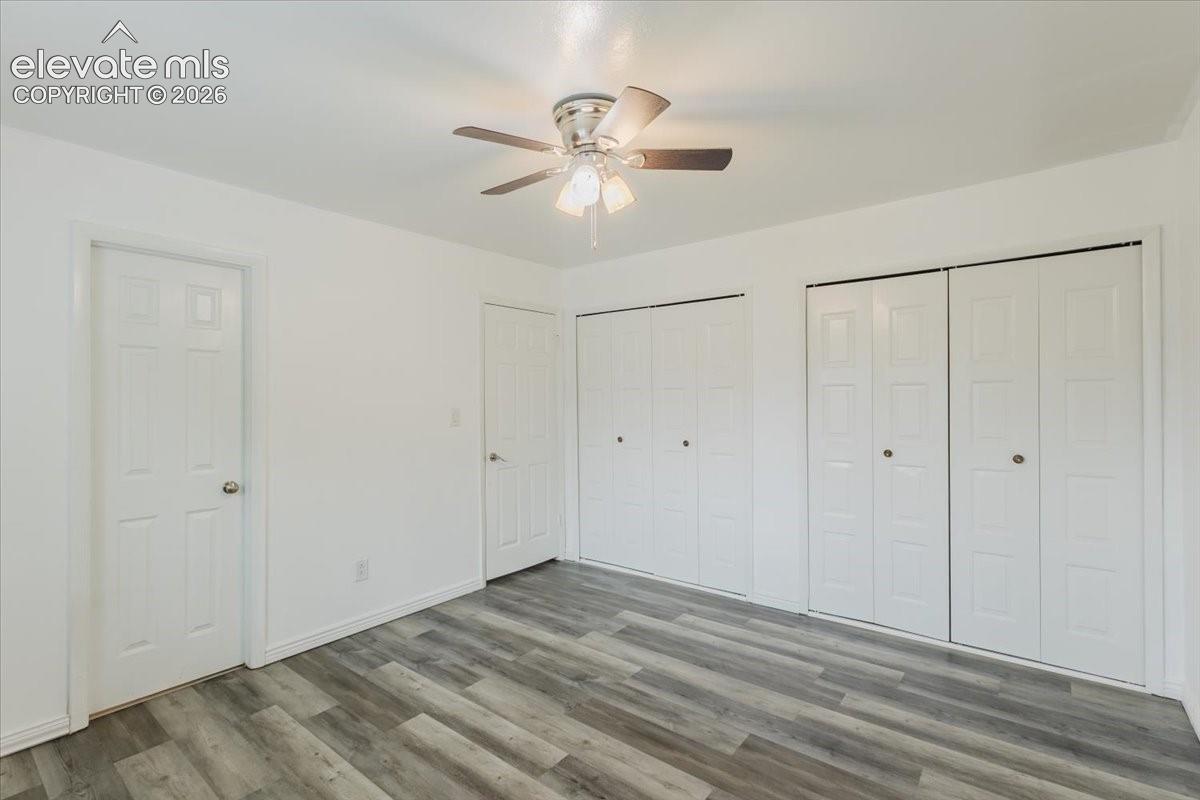 Room featuring wood-finish flooring, a ceiling fan with light kit, and white walls