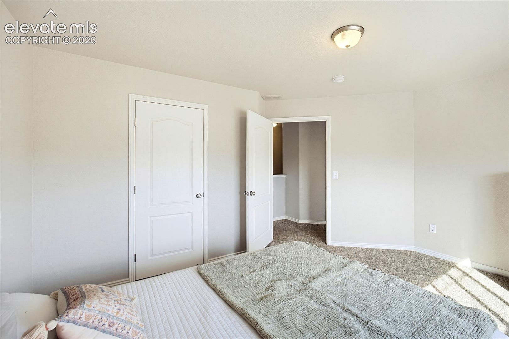 Neutral-toned interior featuring wall-to-wall carpeting, crisp off-white wall finishes, and a classic two-panel interior door