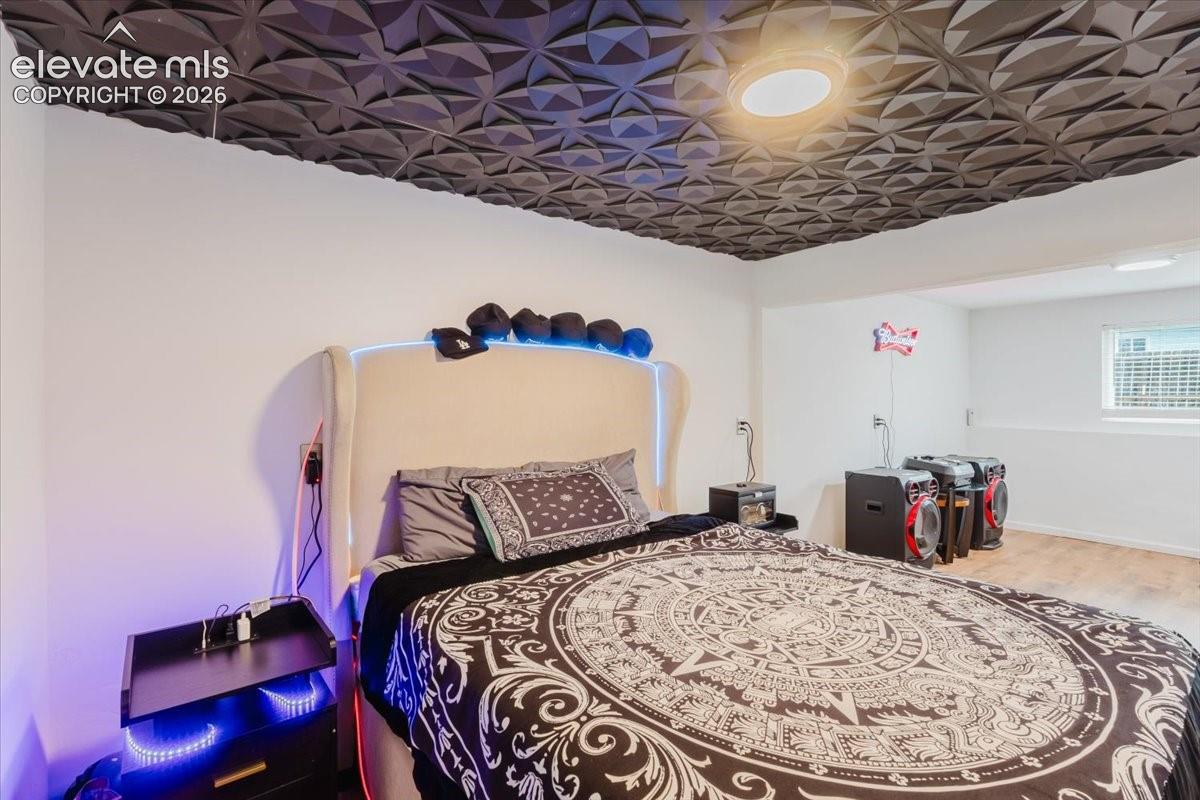 Bedroom featuring a dimensional dark ceiling, recessed lighting, white walls, and wood-finish flooring