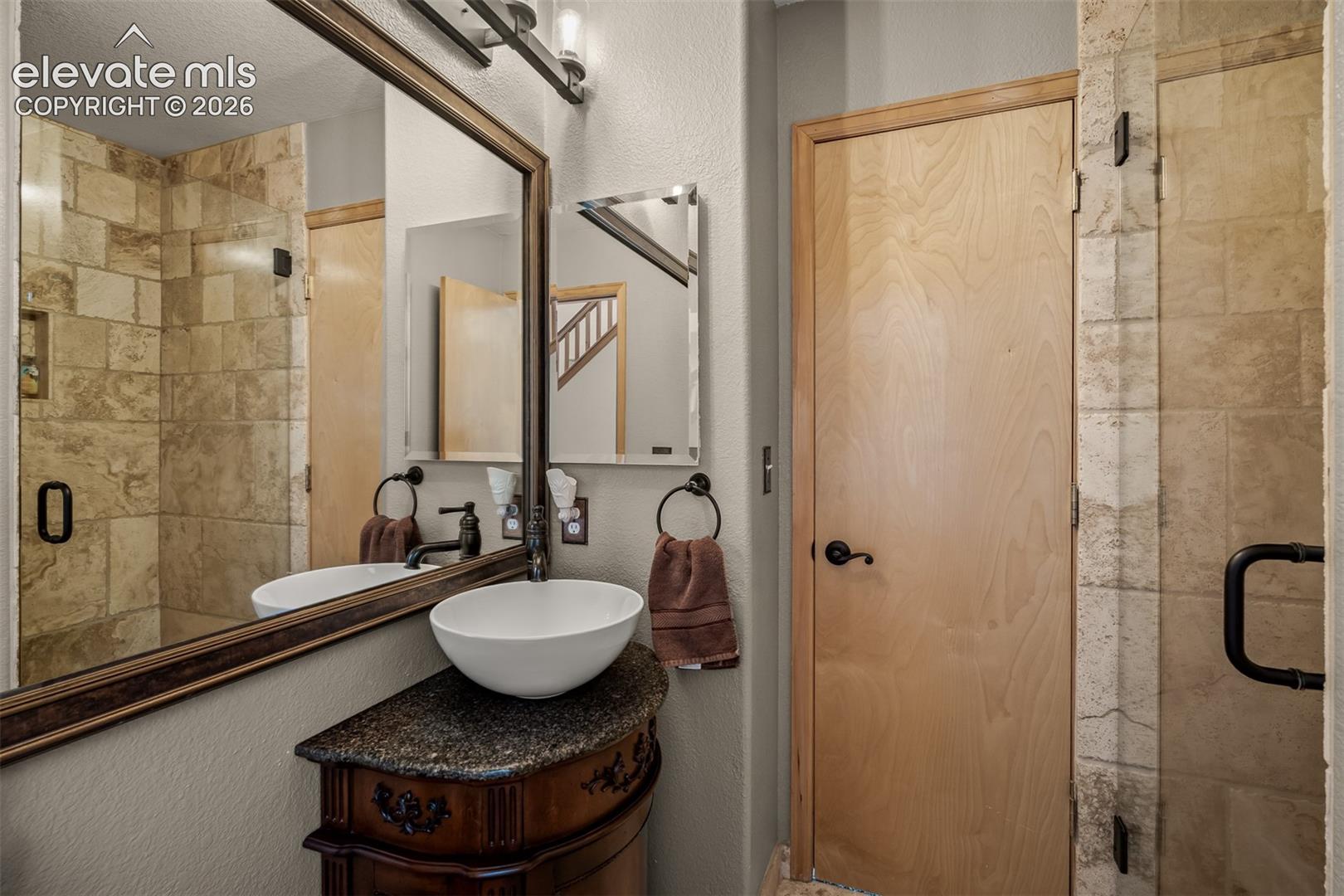 Modern vanity with a vessel sink and dark stone countertop in the main floor 3/4 bath.