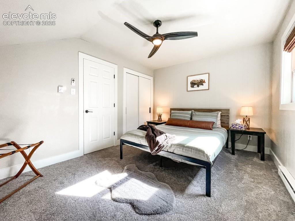 Carpeted room featuring a ceiling fan with integrated lighting, a paneled door, a sliding closet door, and a window with blinds