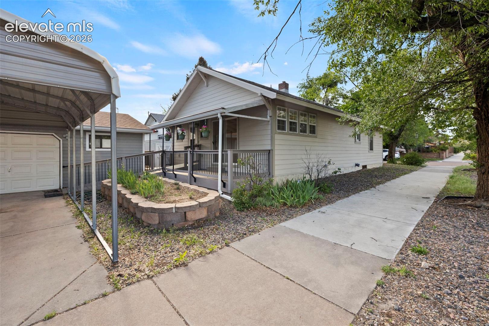 Siding exterior with multiple windows, covered front porch, integrated ramp access, and a stone-lined planter