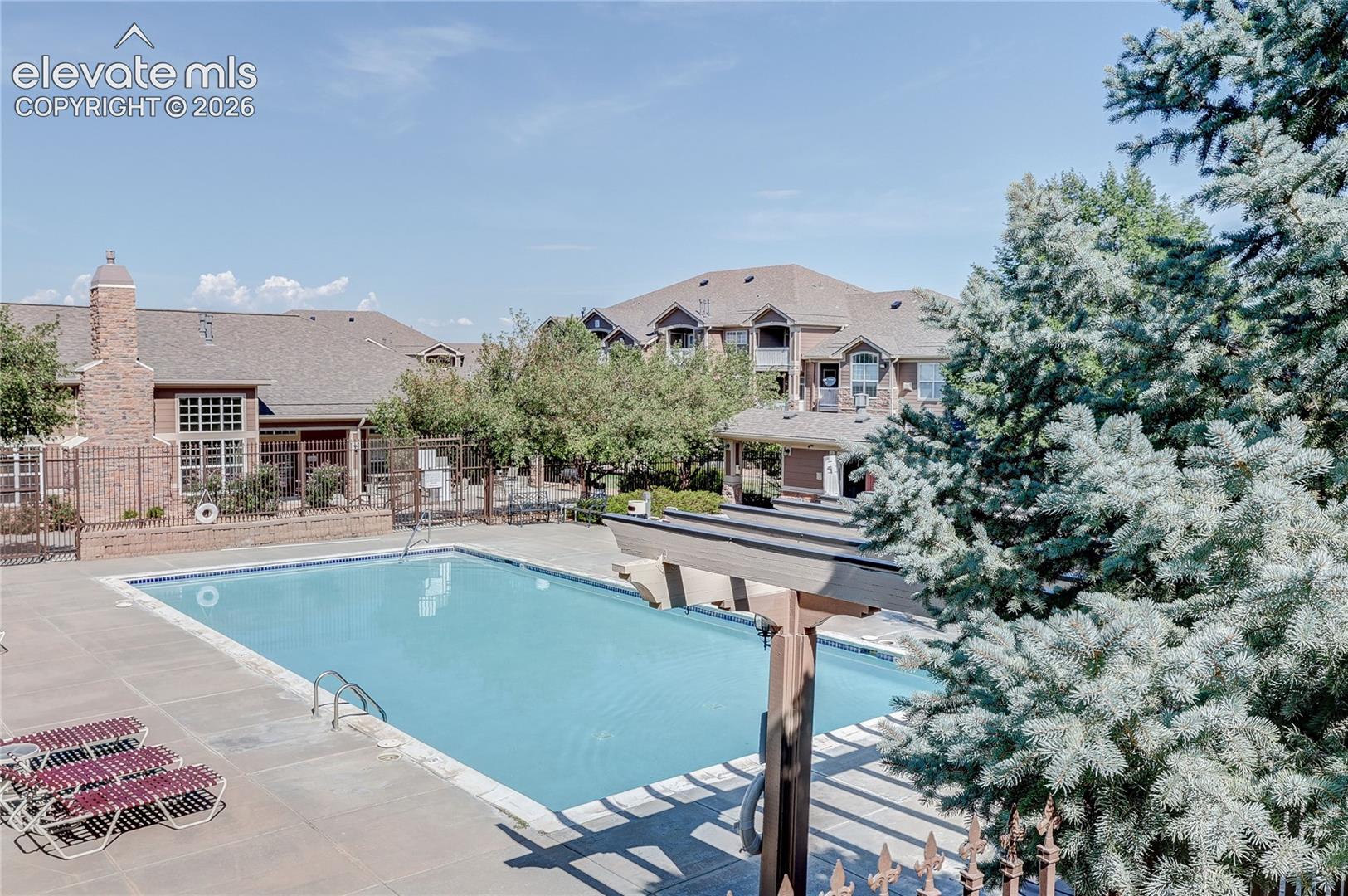 Outdoor swimming pool with concrete decking, pergola, and brick masonry chimneys