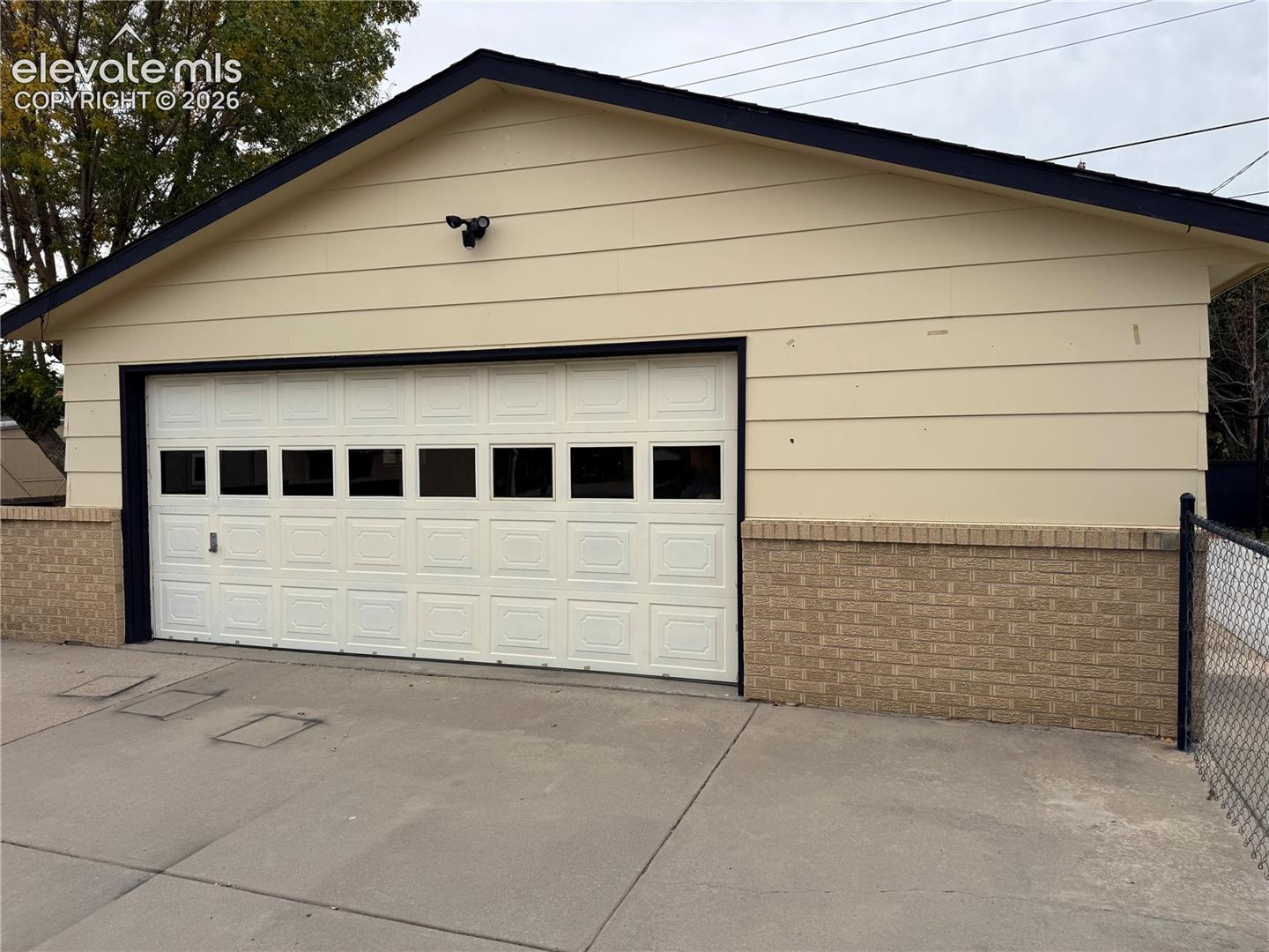 Detached garage with lap siding, masonry lower-wall detailing, concrete driveway, and multi-pane overhead door