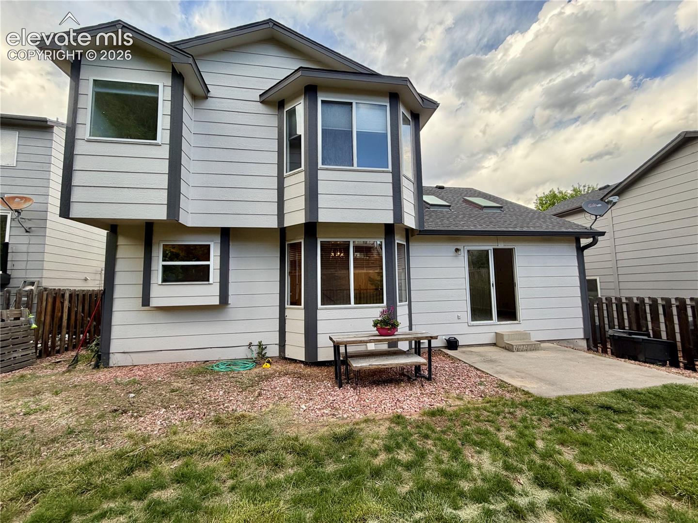 Rear exterior featuring light-colored horizontal siding and dark trim accents