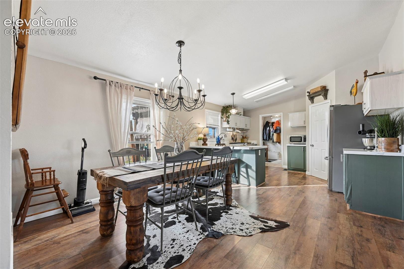 Dining area featuring wood-finish flooring, a decorative metal chandelier, and recessed cabinetry with solid-surface countertops