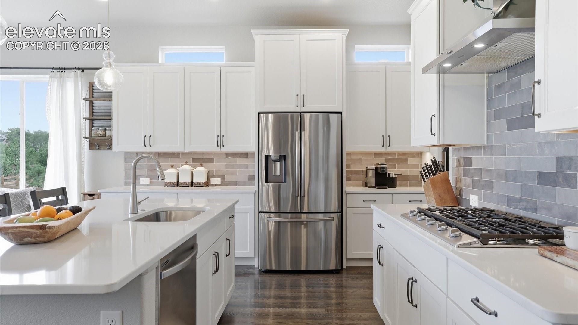 A KITCHEN DESIGNED TO IMPRESS — Gourmet cooking meets sophisticated design with a professional-style gas range, stunning quartz surfaces, and elegant designer tile.