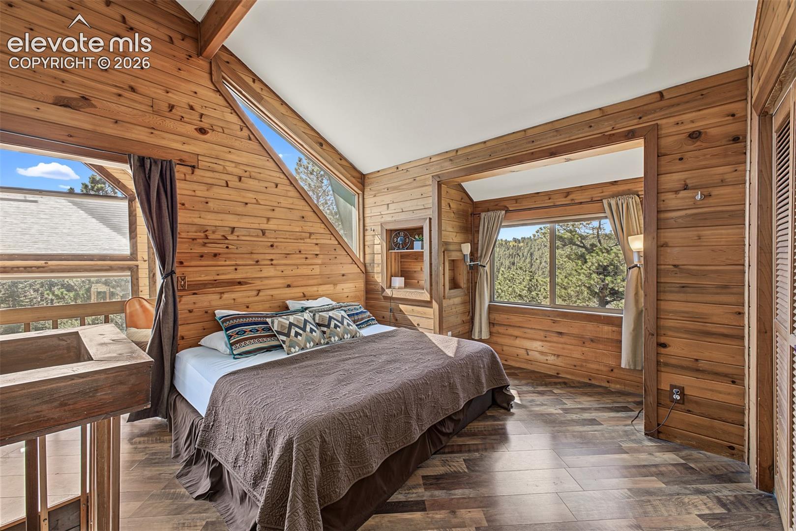 Wood-paneled walls and ceiling beams, wood-finish flooring, built-in shelving, and multiple windows