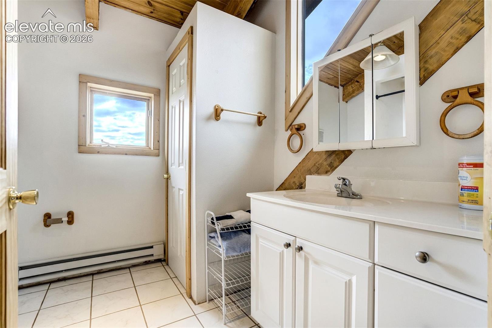 Bathroom featuring a single vanity with white cabinetry, an integrated sink, and a mirrored medicine cabinet