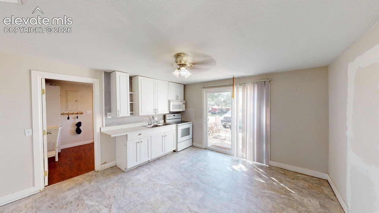 Kitchen area featuring white cabinetry, a single basin sink, and a built-in microwave