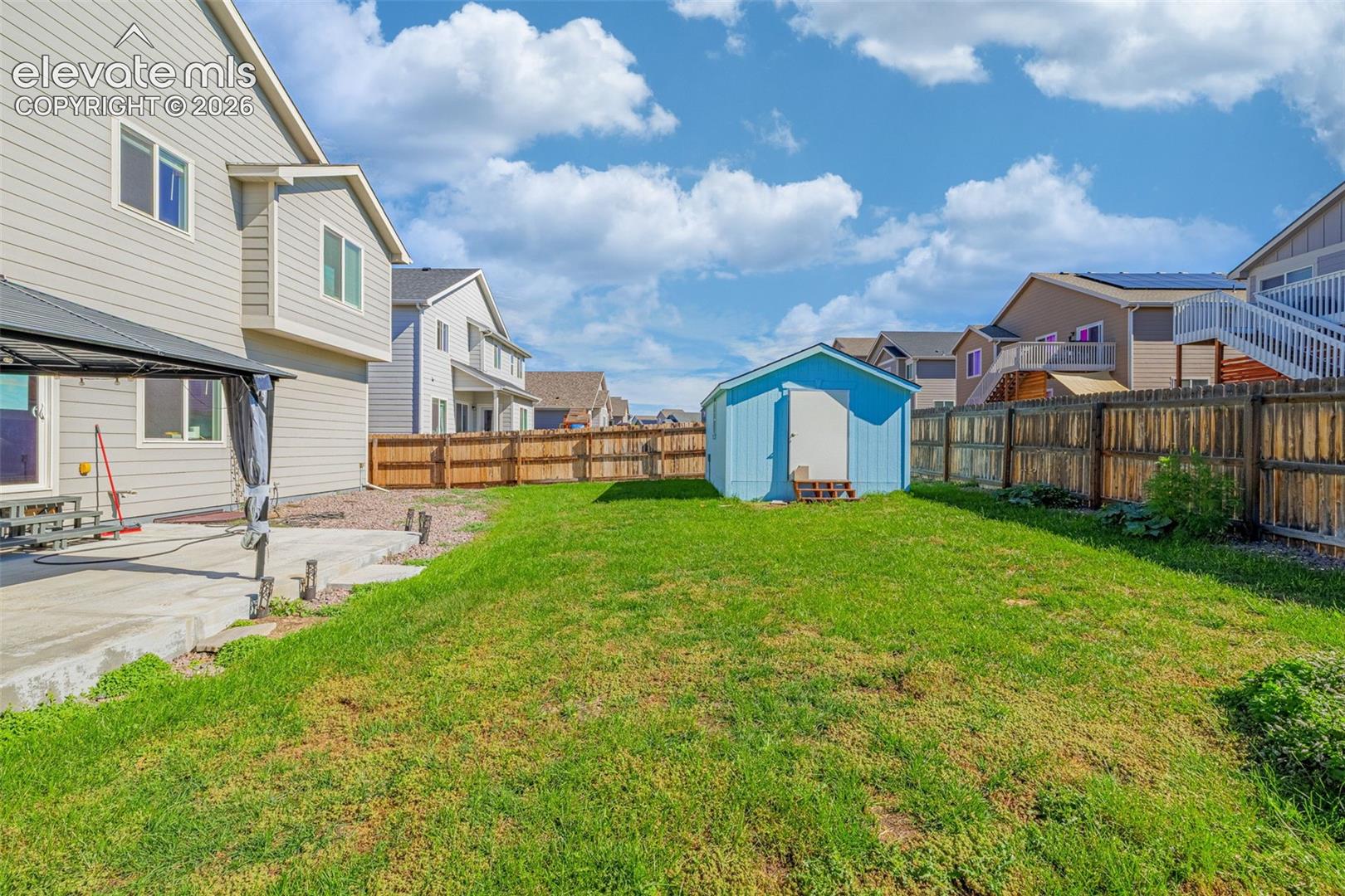 Expansive green lawn with a privacy fence and a detached storage shed