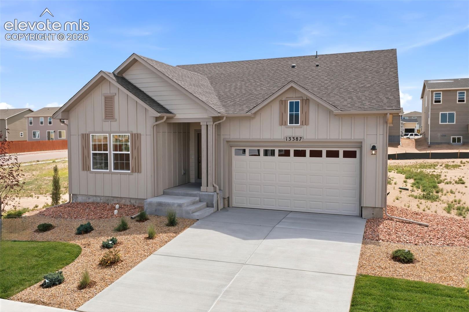 Single-story exterior featuring vertical board-and-batten siding, a gabled roofline, decorative window shutters, and a two-car garage with transom window accents