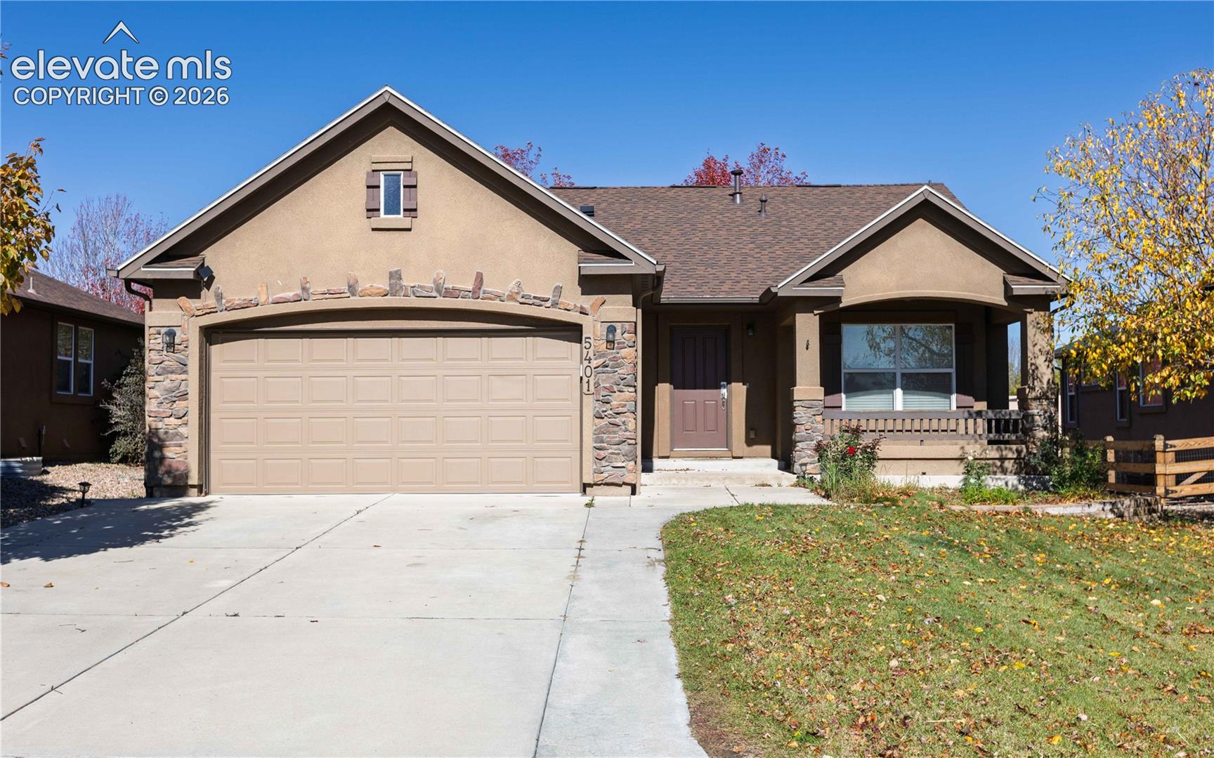 Stucco exterior featuring stacked stone masonry accents, a shingled roof, attached two-car garage, and a covered front porch