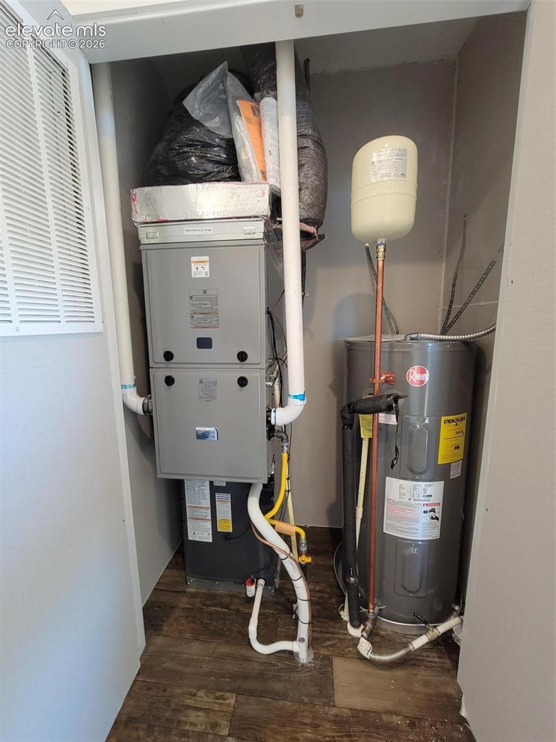 Utility closet housing a forced-air furnace unit and a water heater tank with integrated pressure expansion vessel and wood-finish flooring